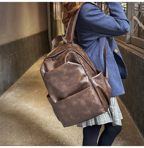 Detail of dark brown vintage PU leather backpack on model in urban street setting