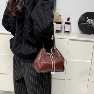 Détail du sac seau bordeaux avec texture tressée, cuir et cordon de serrage avec perles