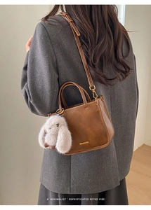 Gros plan d'un sac seau vintage en cuir marron avec un charme lapin blanc sur un mannequin