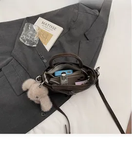 Draufsicht auf das Innenleben der dunkelbraunen Handtasche mit Fächern und Anhänger
