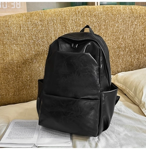 Macro shot of black PU leather backpack with vintage texture on a white fabric surface