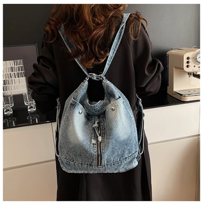 Detail eines hellblauen Denim-Rucksacks mit Quasten und Nieten an einem weiblichen Model