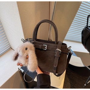 Detail der kaffeebraunen Wildleder-Handtasche mit Silberschnallen und Plüschhasen