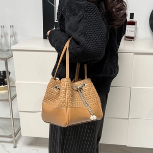 Détail du sac seau marron caramel avec texture en cuir tressé et breloques de perles chic