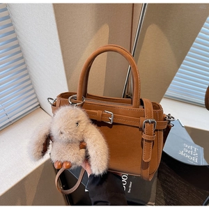 Detailaufnahme der braunen Kunstledertasche mit Silberbeschlägen und Plüschhasen-Anhänger