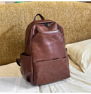 Close-up of vintage brown PU leather backpack on a bed with lifestyle accessories