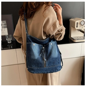 Detail der blauen Denim-Tragetasche mit Nähten und Nieten, getragen von einem Modell