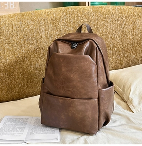 Detailed view of brown PU leather backpack with lychee grain texture and zipper pocket