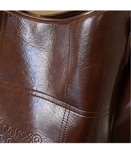 Detailansicht der dunkelbraunen Ölwachs-Leder-Eimertasche mit Logo-Prägung und feinen Nähten