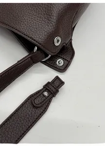Détail macro du sac en cuir grainé avec anneau en D argenté et bandoulière amovible