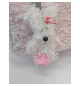 Close-up of a white plush rabbit charm with bone hairpin on a pink faux fur bag