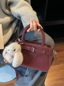 Dunkelrote Handtasche aus mattem Leder mit flauschigem Hasen-Anhänger und silberner Schnalle