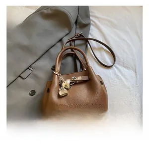 Détail du sac seau en cuir marron à motif litchi avec breloques cœur et serrure en métal