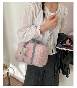 Detailed macro view of pink plush crossbody bag featuring cute bunny charm and grey straps