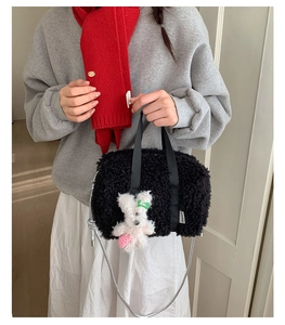 Detail of plush black shoulder bag with cute rabbit charm and silver metal chain strap