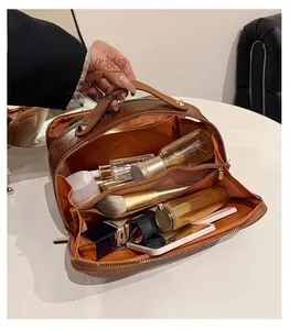 Close-up of the interior compartments in a brown crocodile texture travel makeup bag