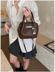 Détail du sac seau en cuir grainé marron foncé avec fermoir argenté et breloques