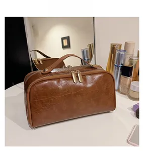 Detailed view of brown crocodile texture leather toiletry bag with golden double zippers