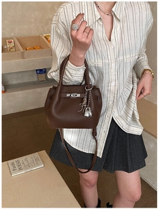 Detailed shot of dark brown litchi grain bucket bag with silver lock and key charm