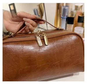 Close-up of smooth double zipper and crocodile pattern leather on brown cosmetic bag