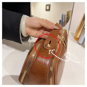 Detailed close-up of premium gold zipper and handle on brown croc-embossed makeup bag