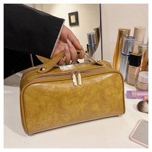 Detail of yellow crocodile pattern makeup bag with gold double zippers on vanity table