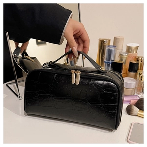 Detail of black crocodile pattern cosmetic bag with golden double zippers and handle