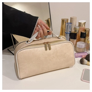 Close-up of cream crocodile pattern makeup bag with gold zippers and sturdy top handle