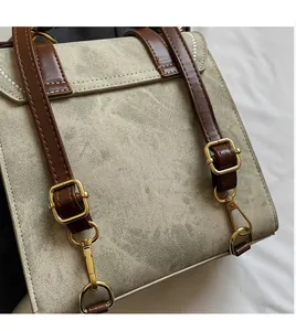 Detail van verstelbare bruine kunstleren schouderbanden en metalen gespen op canvas tas