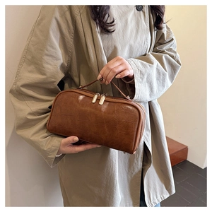 Detail showing the brown crocodile embossed texture and golden double zipper of the travel bag