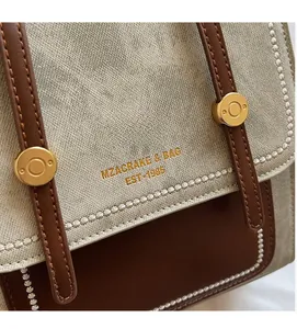 Detail van vintage canvas schoudertas met lederen bies en gouden metalen accenten