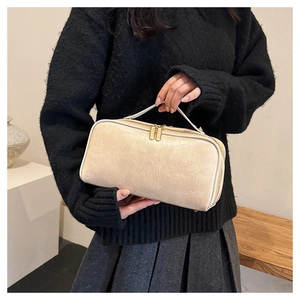 Close-up of beige croco pattern travel pouch with gold zipper held by a model
