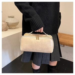 Crocodile embossed beige travel bag with double gold zippers held by a person