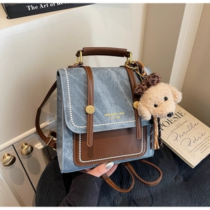 Detail van vintage denim crossbodytas met imitatieleer en pluche hondenhanger decoratie