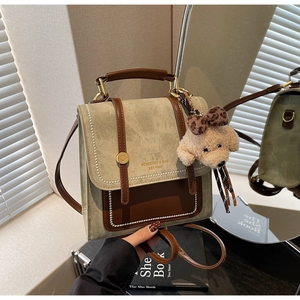 Detail van vintage canvas crossbodytas met leren bies en een pluchen beer bedeltje