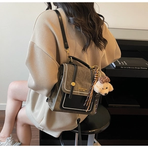 Detail van vintage crossbodytas met parelmoer rand, merklogo en pluche puppyhanger