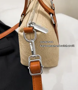 Detail of woven tote bag with silver metal hooks and brown leather strap attachments