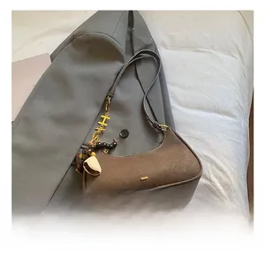 Détail du sac hobo en cuir mat marron avec breloque lettre H dorée et bandoulière réglable