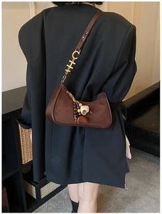Detail of brown suede crescent bag featuring vintage charm tassel and gold CH logo