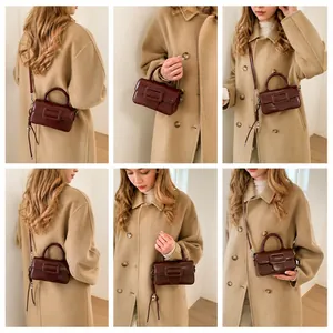 Detail view of burgundy leather square crossbody bag styled with a beige coat