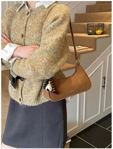 Brown leather hobo bag with unique beaded heart charm shown in a cozy indoor setting