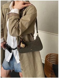 Detail of olive green matte leather shoulder bag with gold hardware and leaf charm