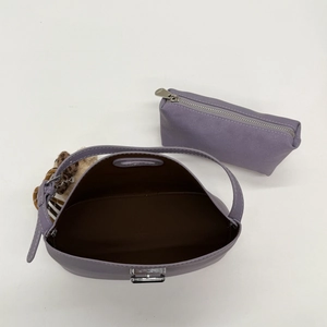 Detail of light purple dumpling bag with brown lining, leopard charm, and mini pouch