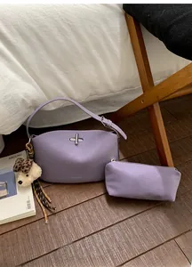 Close-up of purple crescent shoulder bag with dog charm and mini pouch on wood floor