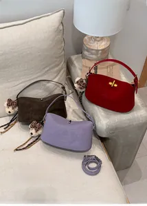 Detail view of suede underarm bags in red, brown, and purple with cute bear charms