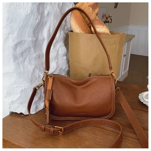 Close-up of brown leather shoulder bag with vintage gold zippers and embossed logo detail
