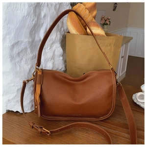 Detail of caramel leather crescent bag with gold zipper and dual shoulder straps