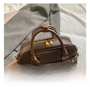 Dettaglio borsa Boston in pelle marrone con cerniere dorate e cuciture bianche a contrasto