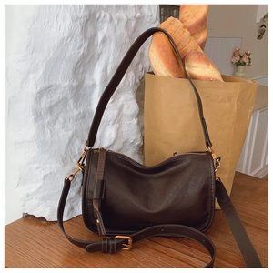 Detail of dark brown leather handbag with gold metal zipper and vintage buckle strap