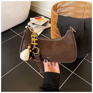 Detailed view of brown PU leather crescent bag featuring gold H pendant and beaded charms